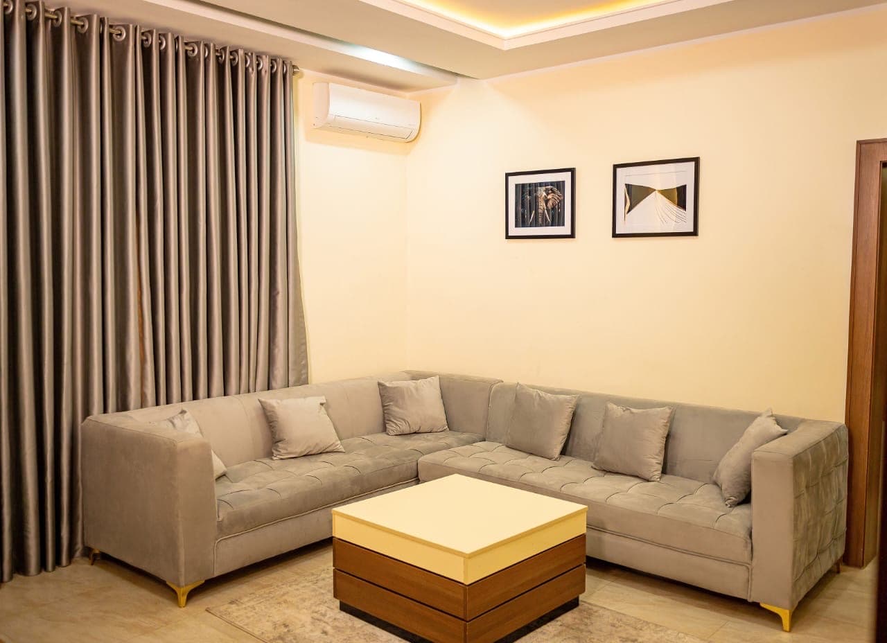 Living room with an L-shaped grey sofa, framed prints and a square coffee table