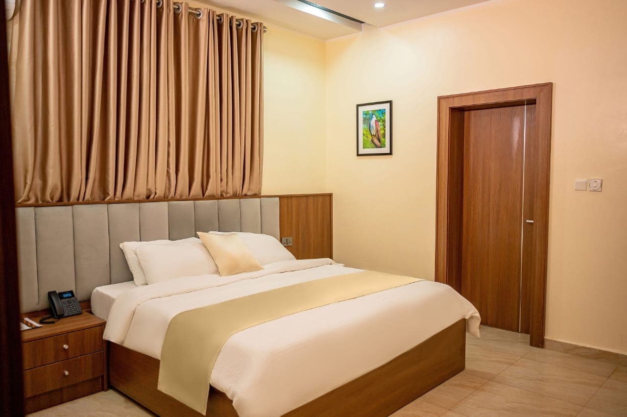 Double bed with a panelled headboard beside a wooden door and curtains