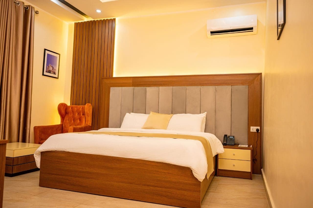 Double bed with an orange armchair and gold wall lighting