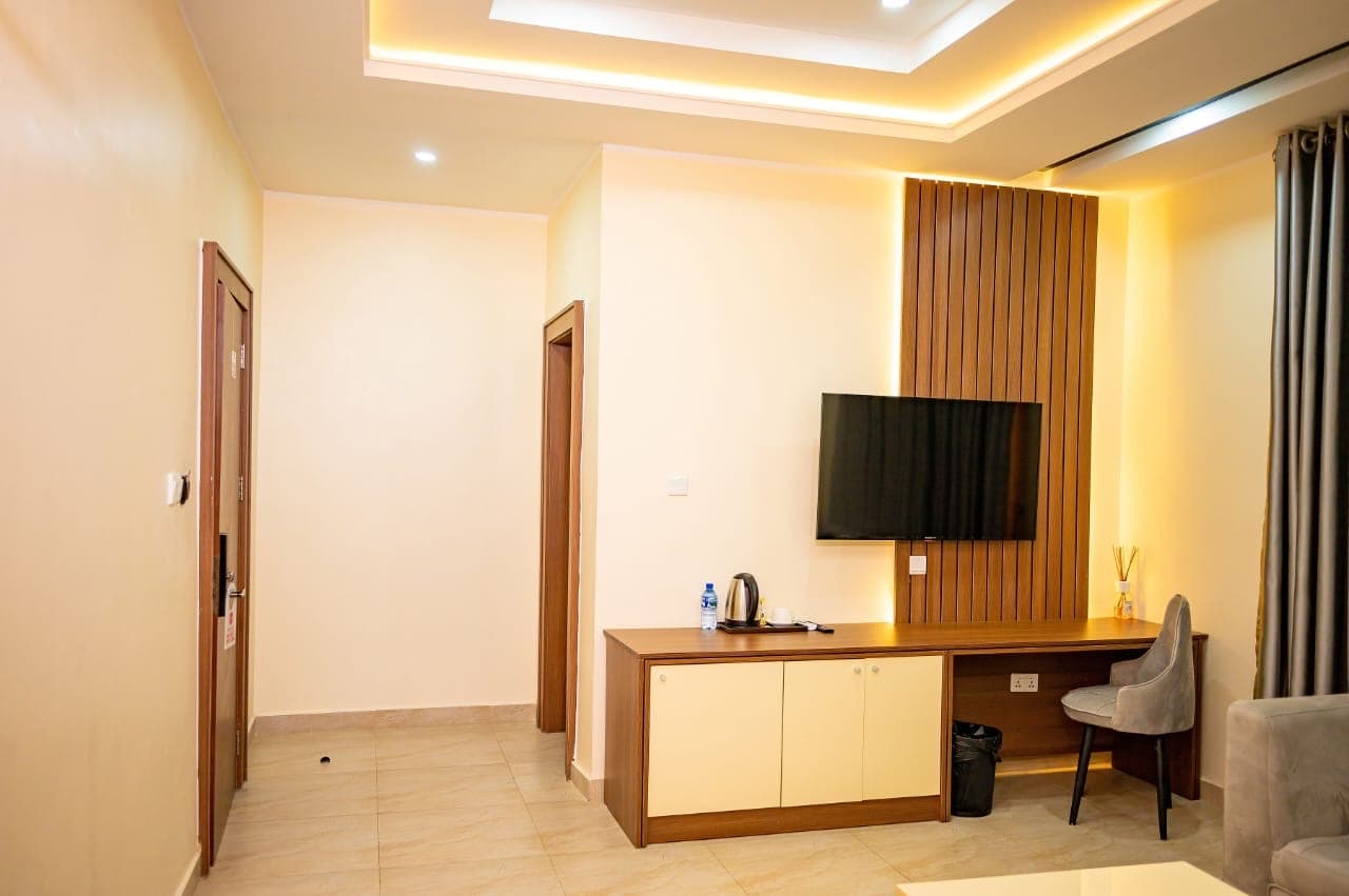 Suite with a wall-mounted TV, desk and a lit ceiling recess