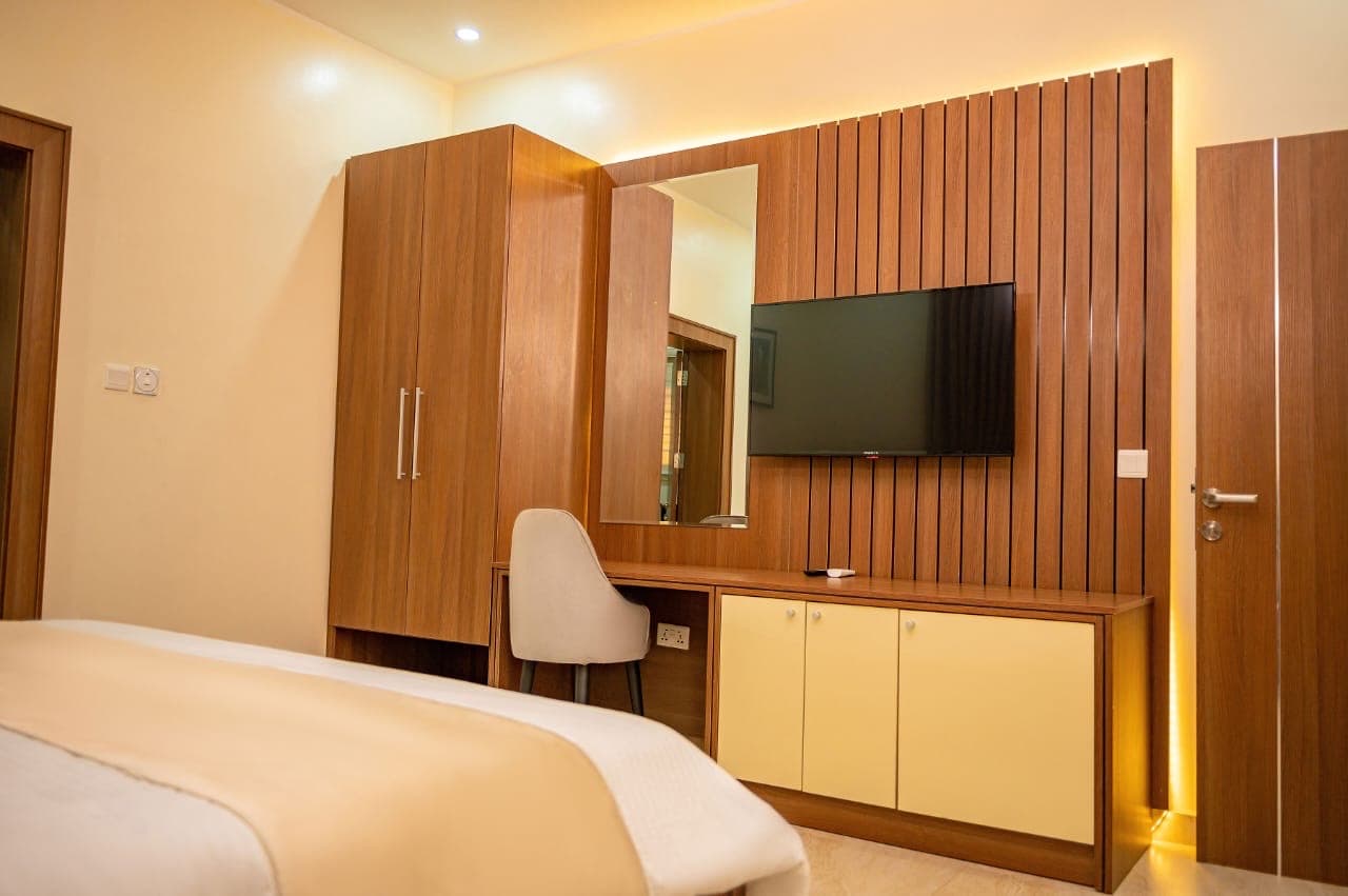 Bedroom with a wooden slatted TV wall, wardrobe and cream drawers