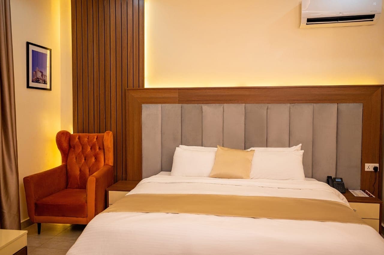 Bed with an upholstered headboard and an orange armchair in the corner