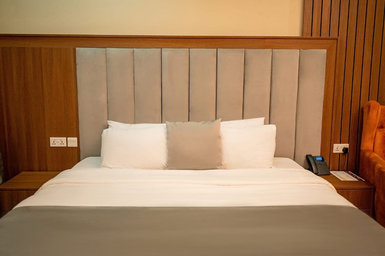 Close-up of a bed with a grey panelled headboard and white pillows