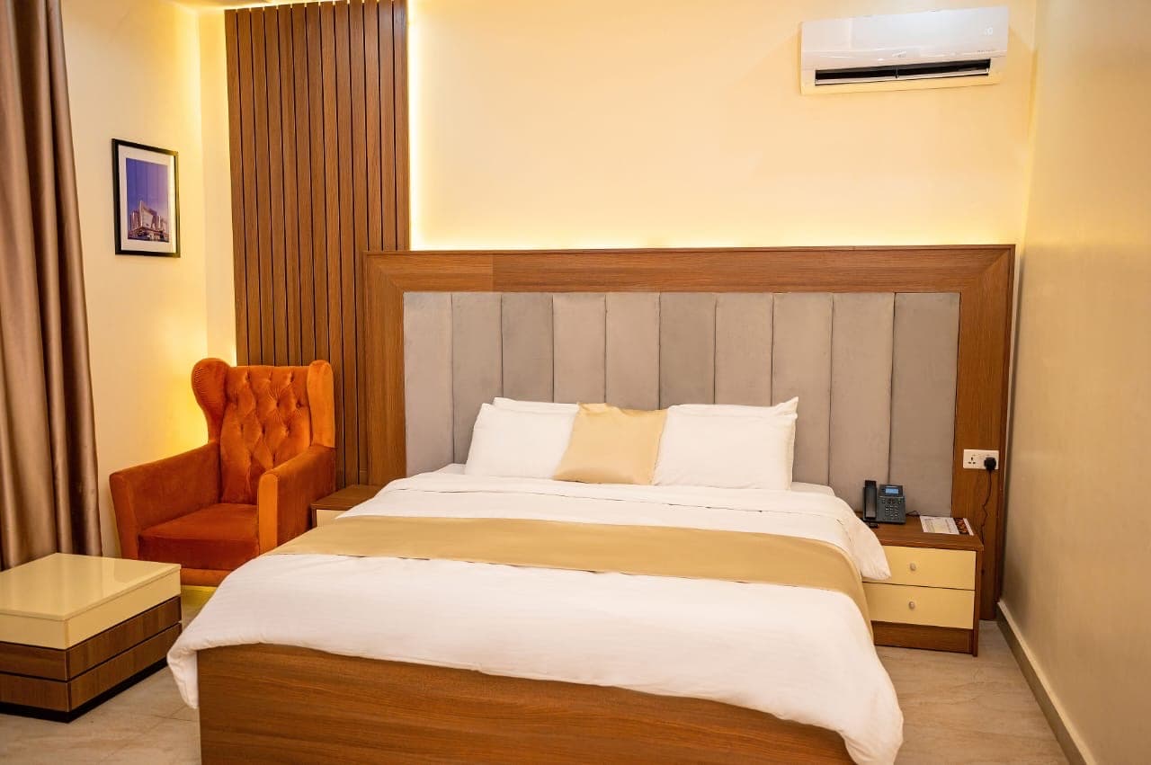 Bedroom with a cream armchair, framed art and a wooden headboard wall