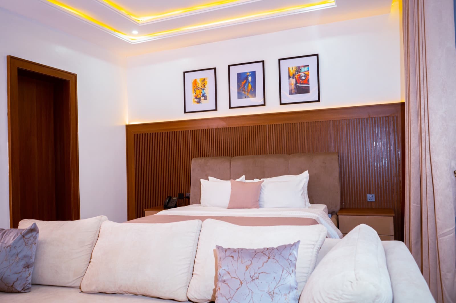 Suite with a bed behind a sofa, framed prints and gold ceiling lighting