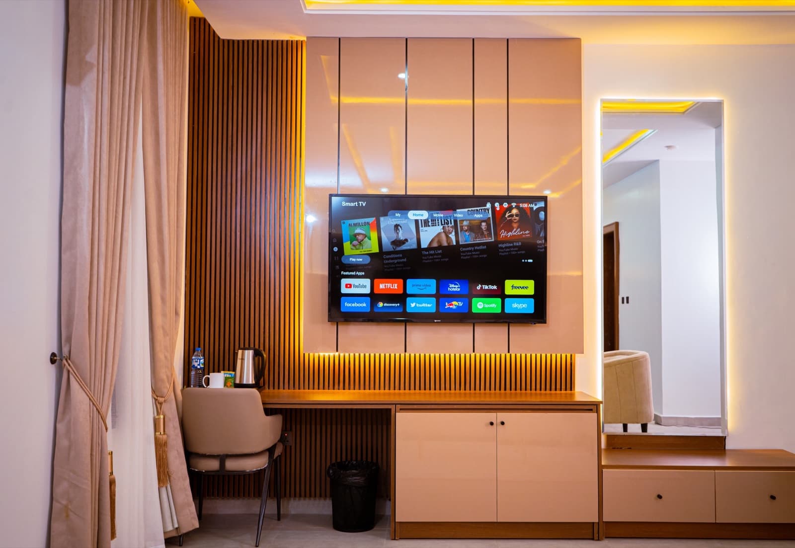 Wall-mounted TV on a ribbed wood panel with a desk and chair
