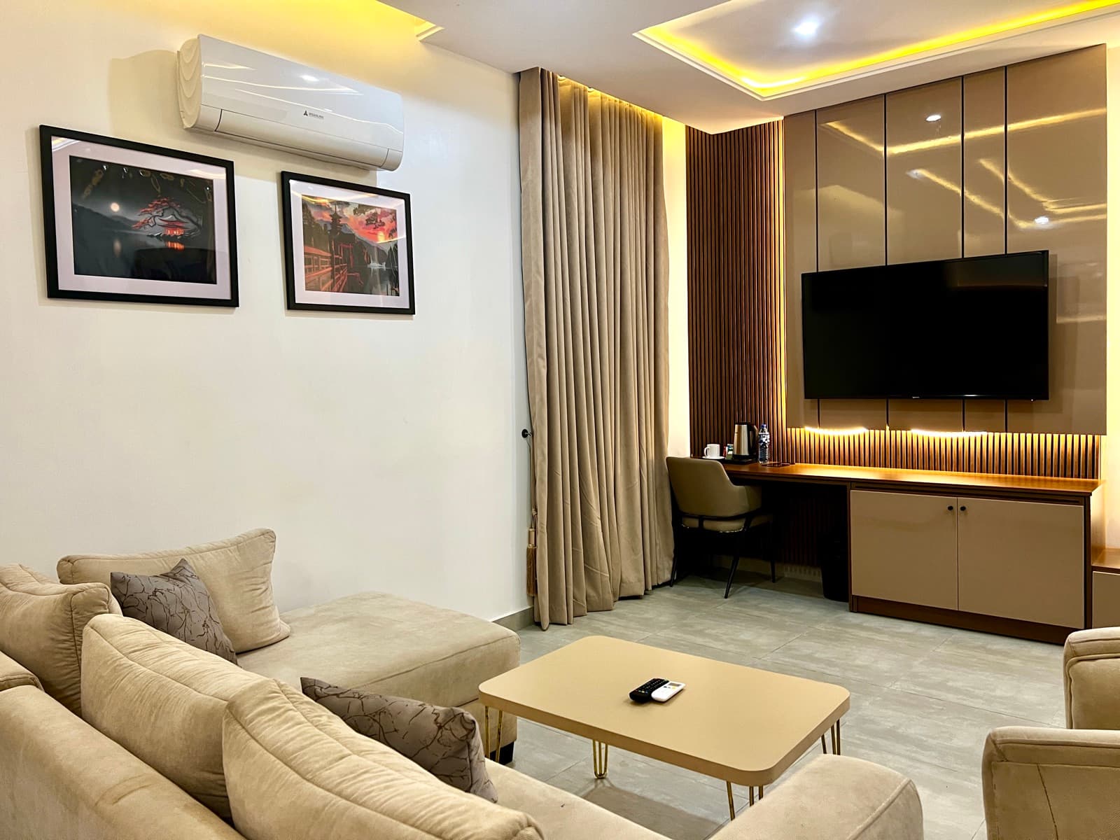 Lounge with a beige sofa, wall art and a TV on a panelled wall