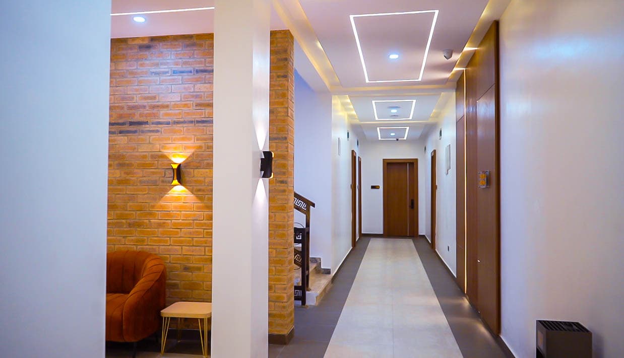 Corridor with a brick wall, an orange armchair and recessed ceiling lights