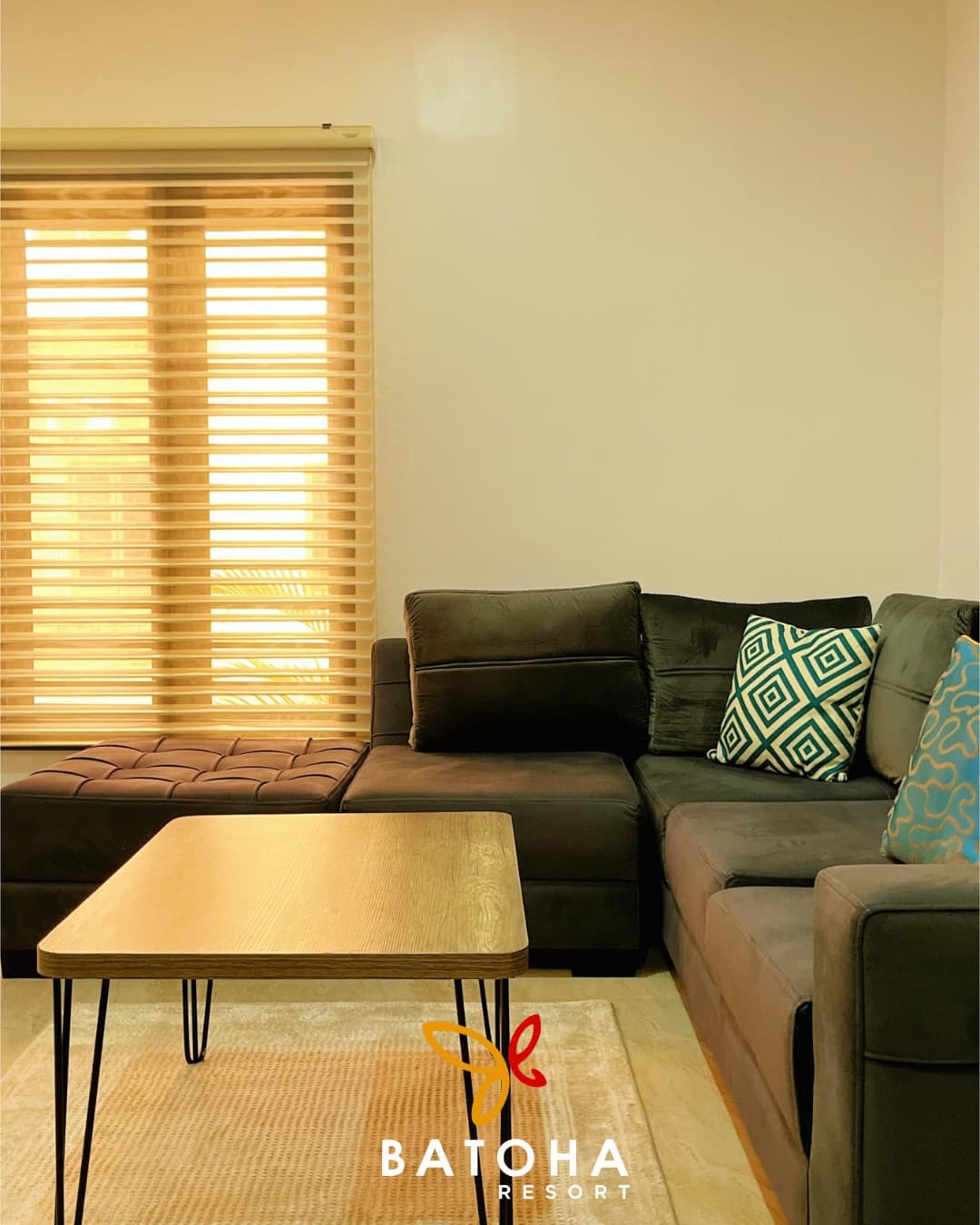 Living room with a grey sectional sofa and a slatted window blind