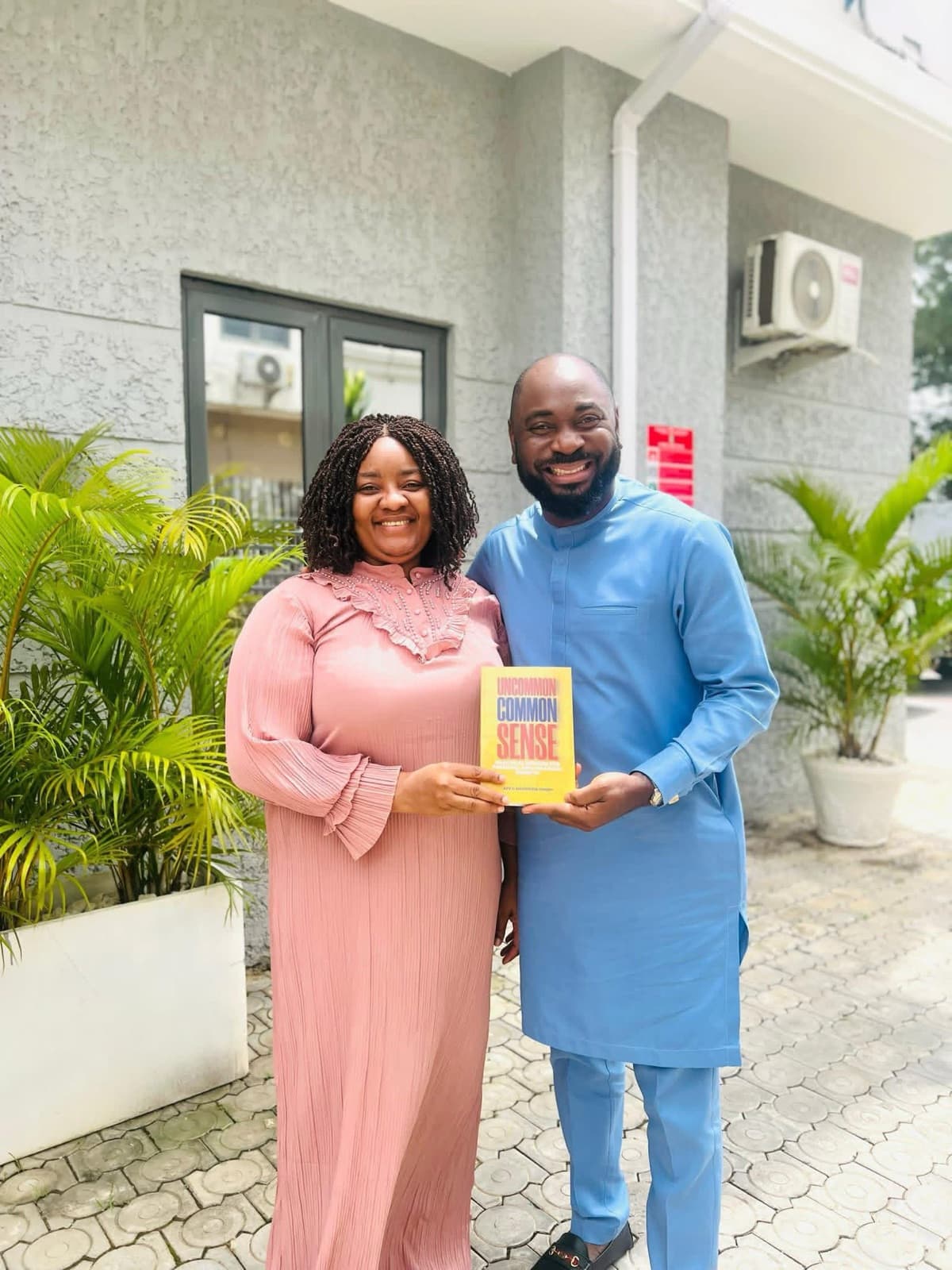 A woman and a man posing outdoors with a copy of Uncommon Common Sense