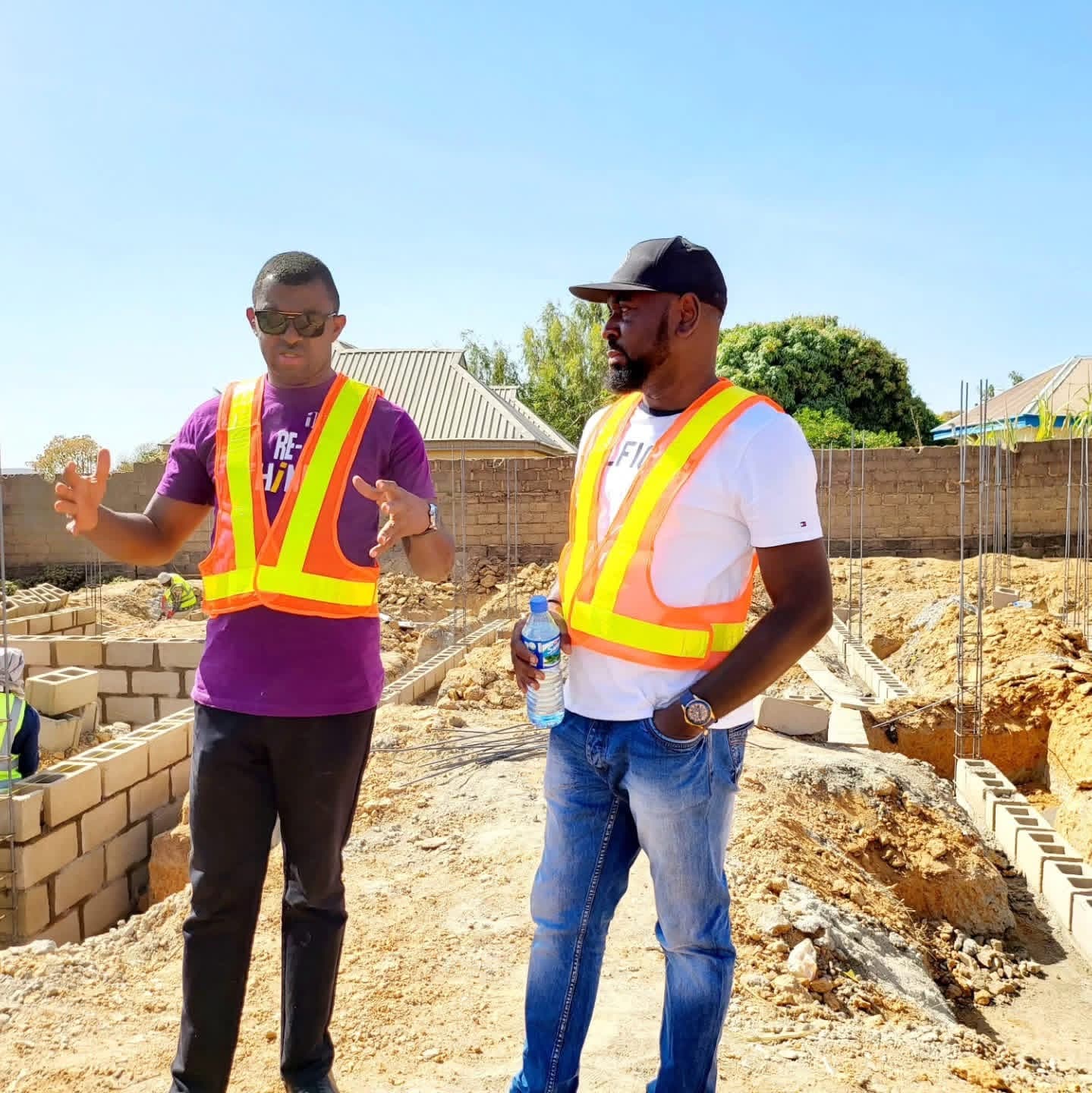 Two men in high-visibility vests talking on a building site