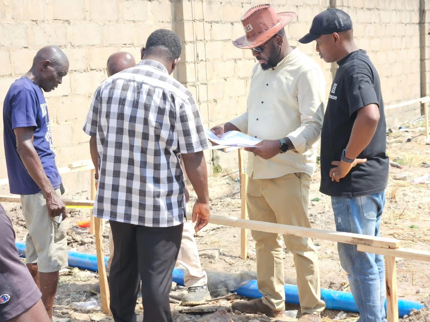 Site team reviewing a plan beside a block wall and a blue pipe