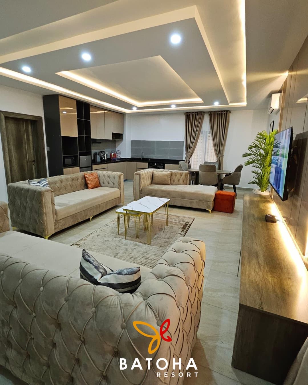 Open-plan living area with tufted sofas under a coffered ceiling