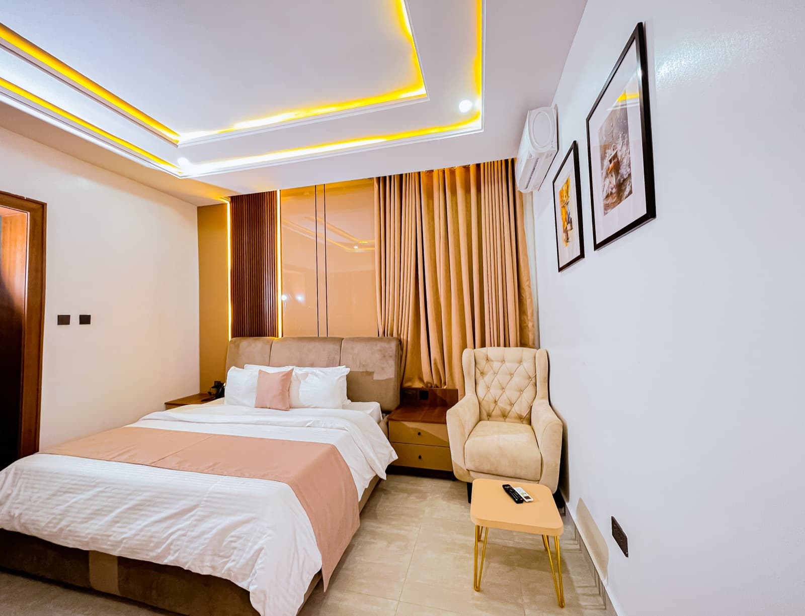 Bedroom with a cream armchair, framed art and a lit ceiling