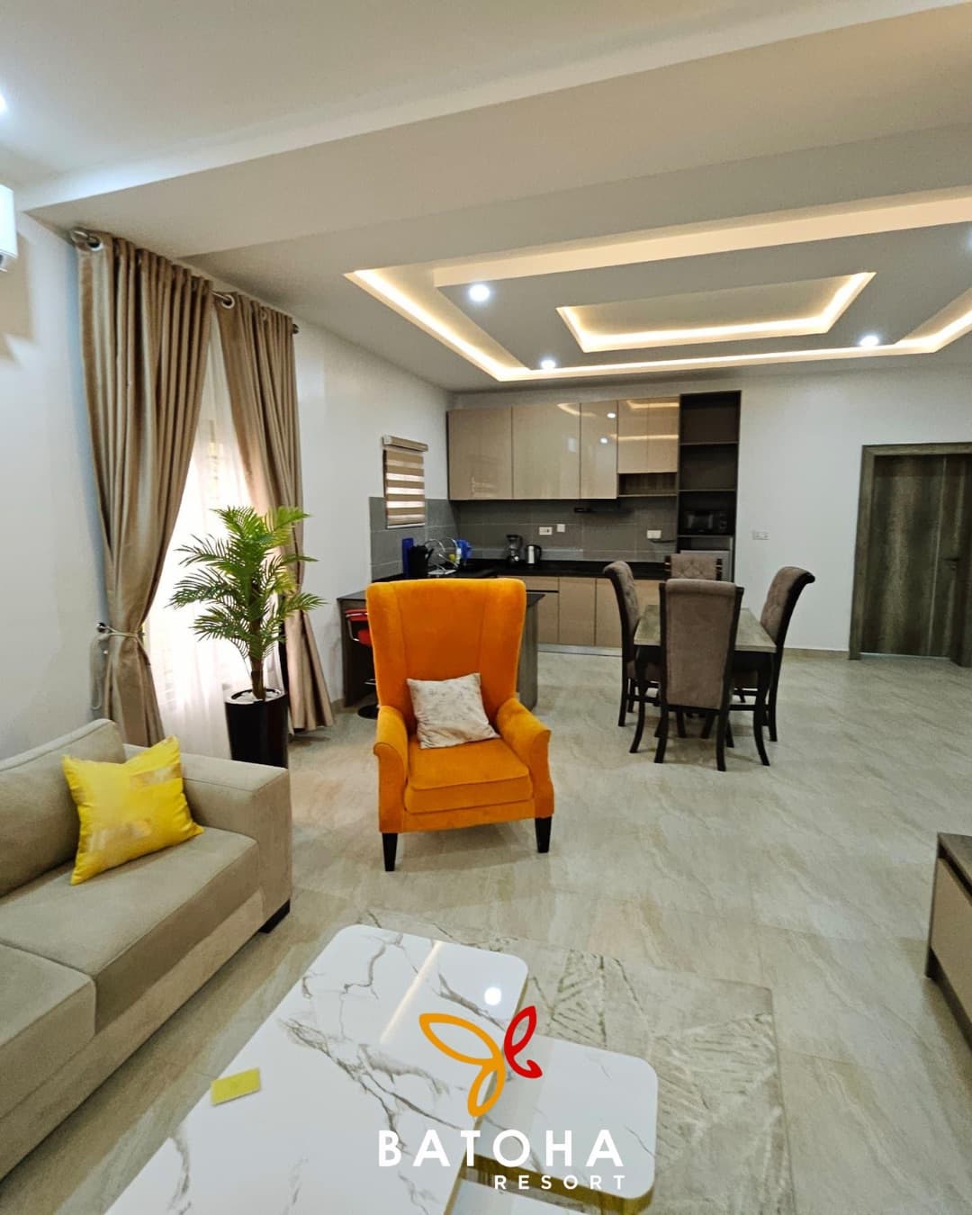 Living room with an orange armchair, marble coffee table and curtains