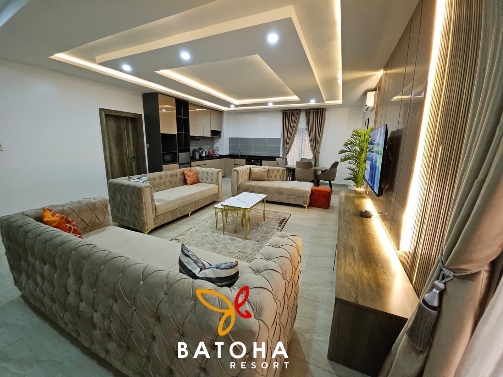 Wide living room with a tufted sofa and an open kitchen beyond