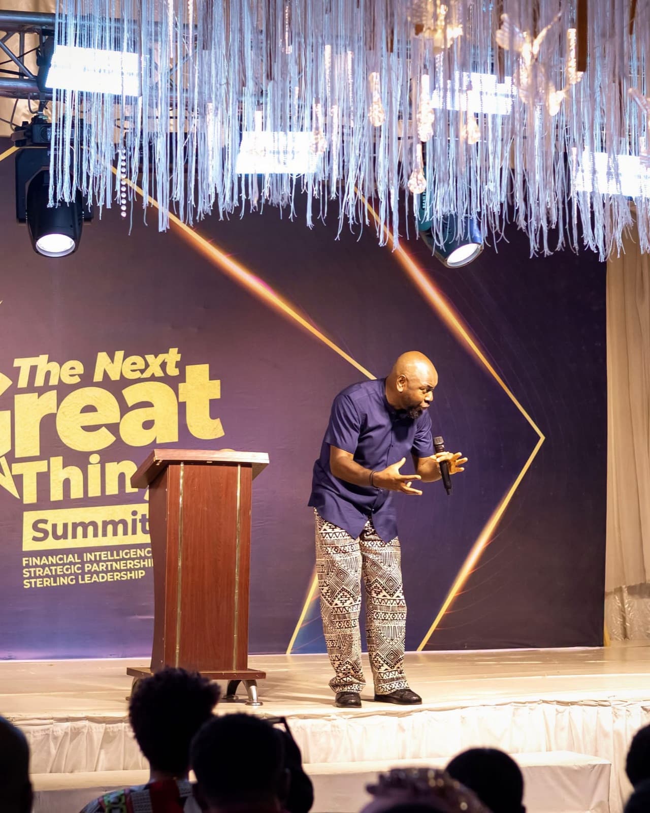 Speaker on stage beside a podium at The Next Great Thing Summit