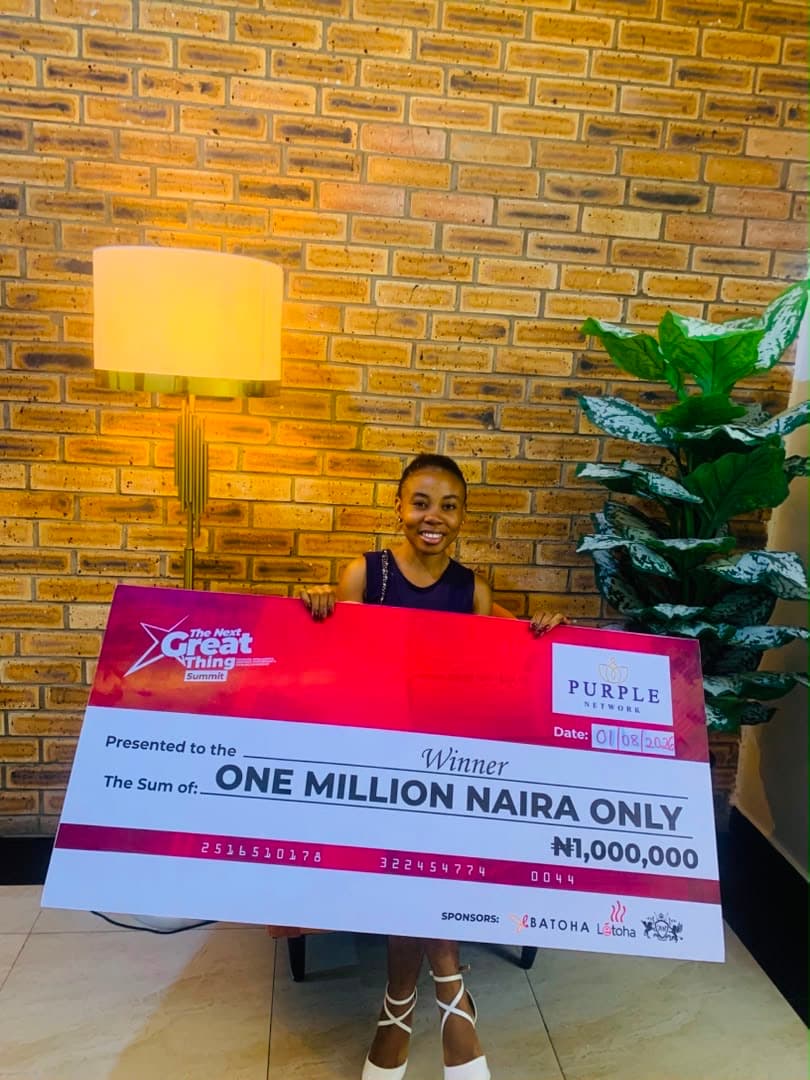 Winner seated holding a one million naira prize cheque