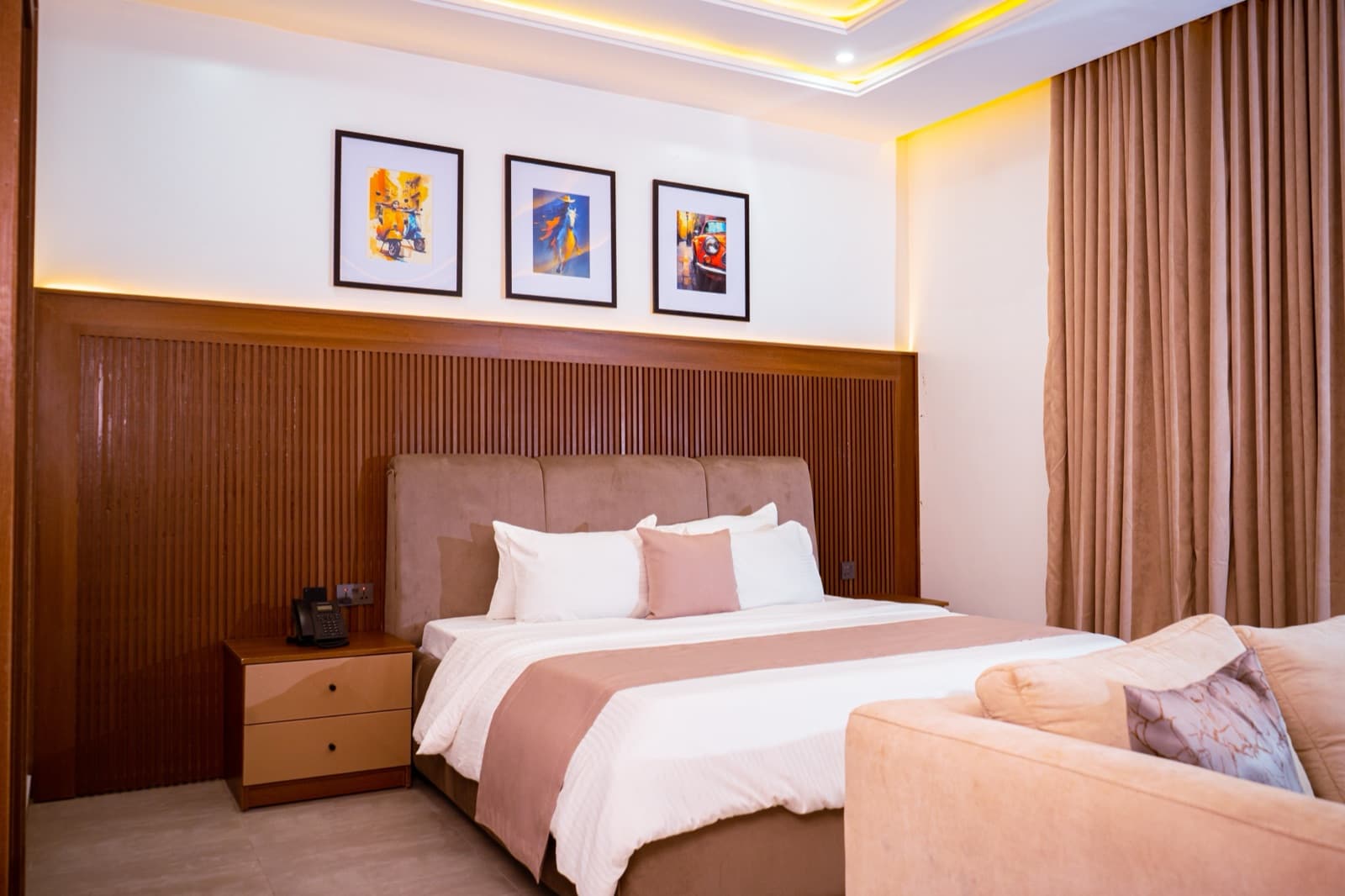 Batoha Royale suite with a made bed, three framed prints and warm cove lighting